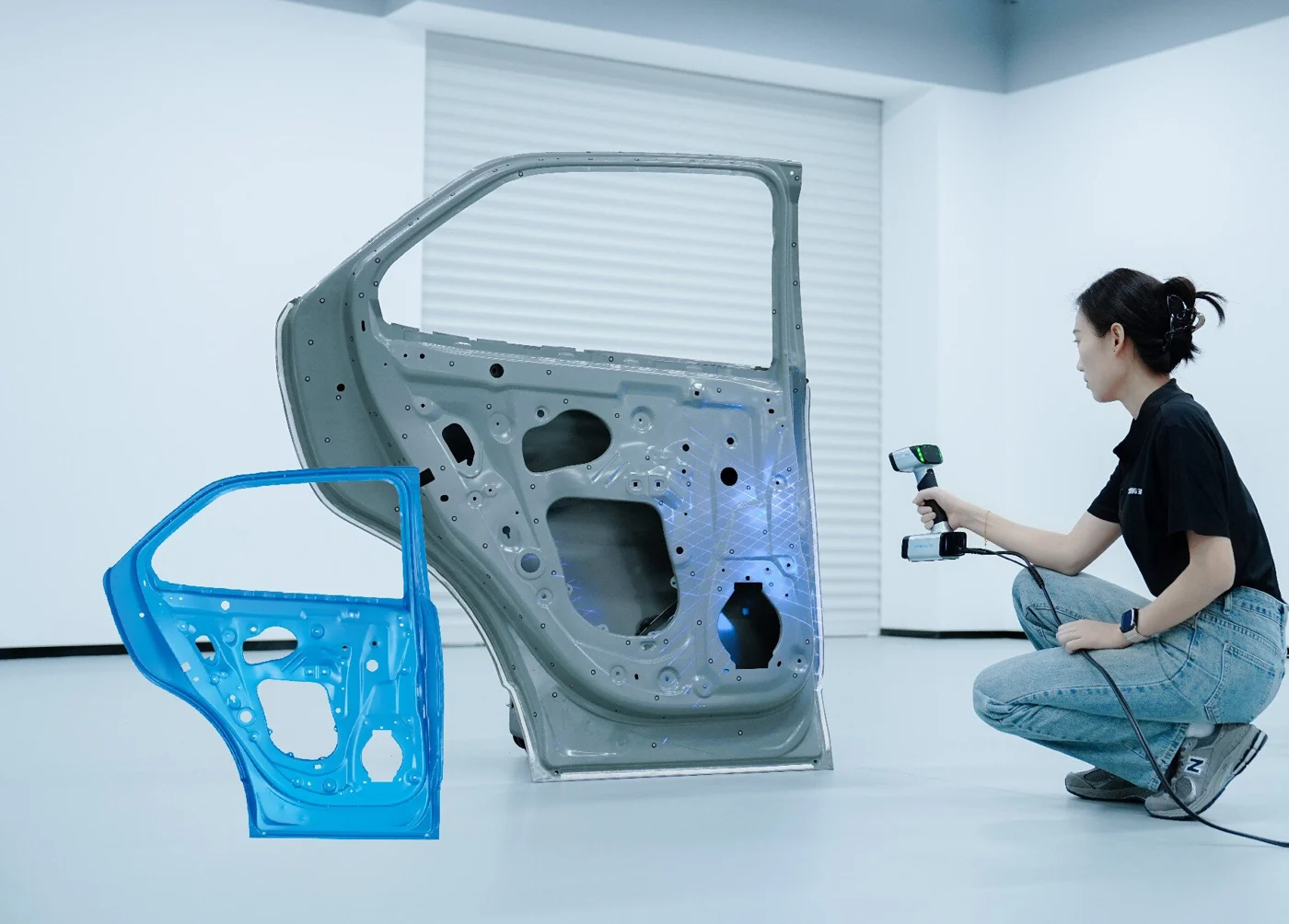 Operator scanning an automotive door panel with the EinScan HX2 beside its blue 3D scan mesh result
