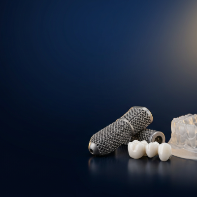 Medical and dental 3D printing banner: titanium implant, ceramic dental crown and resin model on a navy studio background with gold glow